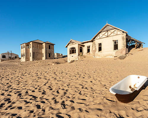 visit the coastal town of Lüderitz and wander through Kolmanskop, a desert ghost town frozen in time and filled with stories