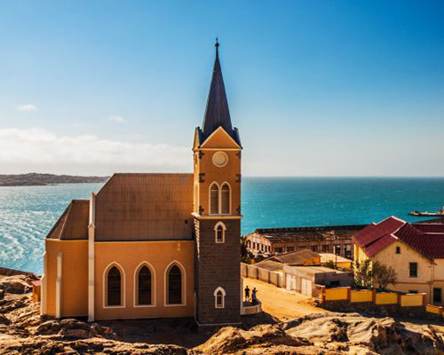 visit the coastal town of Lüderitz and wander through Kolmanskop, a desert ghost town frozen in time and filled with stories